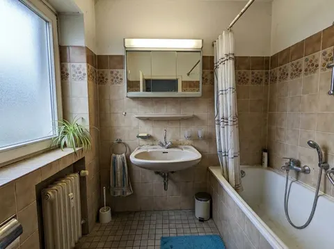 Beispielfoto eines alten Badezimmers mit beigen Fliesen und Badewanne vor der Sanierung
