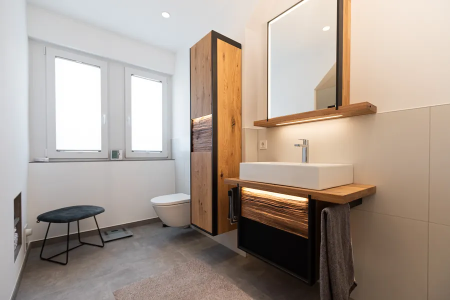 Saniertes Bad in Wadersloh mit Waschtisch aus Eiche, beleuchtetem Spiegel, Hochschrank und Wand-WC