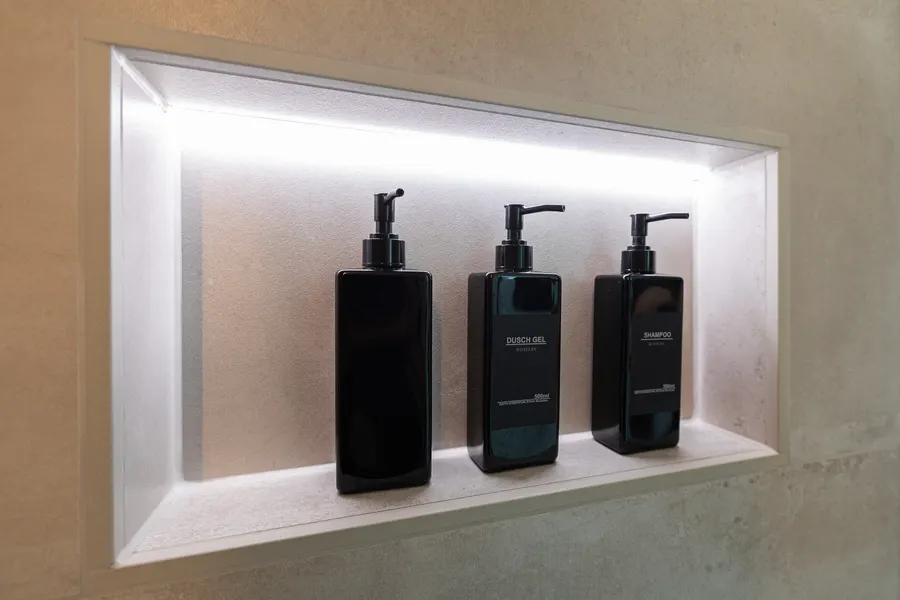 Bodengleiche Dusche mit schwarzer Armatur und Lichtleiste in der Wand