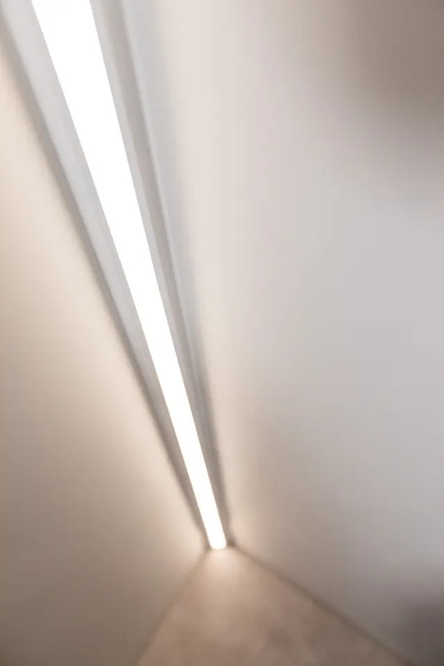 Lichtleiste im Übergang von Wand und Boden in einem sanierten Bad